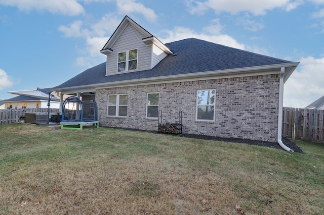 back of house featuring a trampoline and a yard