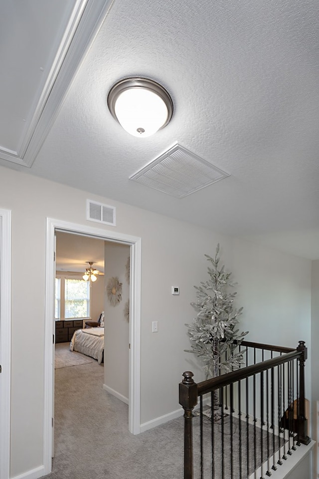 hall featuring a textured ceiling and light carpet