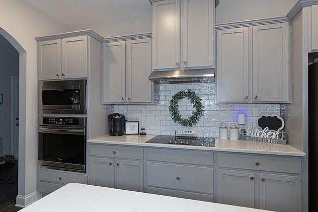 kitchen featuring gray cabinets, appliances with stainless steel finishes, and tasteful backsplash