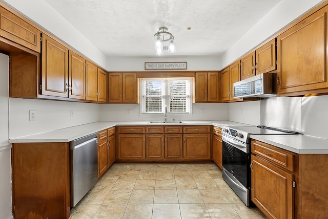 kitchen with stainless steel appliances, sink, a textured ceiling, and light tile patterned floors