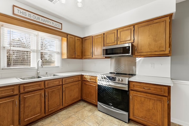 kitchen featuring stainless steel appliances, sink, light tile patterned floors, and a textured ceiling