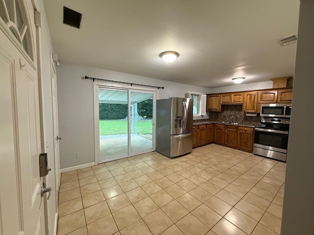 4229 Empire St, Columbus, GA 31907 - kitchen featuring appliances with stainless steel finishes, dark countertops, backsplash, and light tile patterned floors