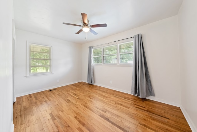 empty room with light wood finished floors, a ceiling fan, and baseboards