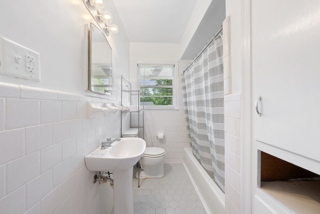 full bathroom featuring tile walls, tile patterned floors, toilet, shower / bath combo with shower curtain, and wainscoting