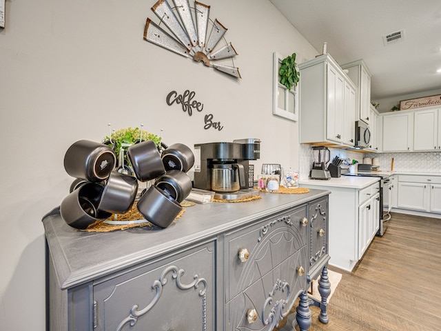 13733 Macon Rd, Upatoi, GA 31829 - kitchen with appliances with stainless steel finishes, light countertops, backsplash, wood finished floors, and white cabinets