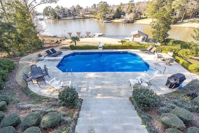 outdoor pool with a diving board, a water view, and a patio area