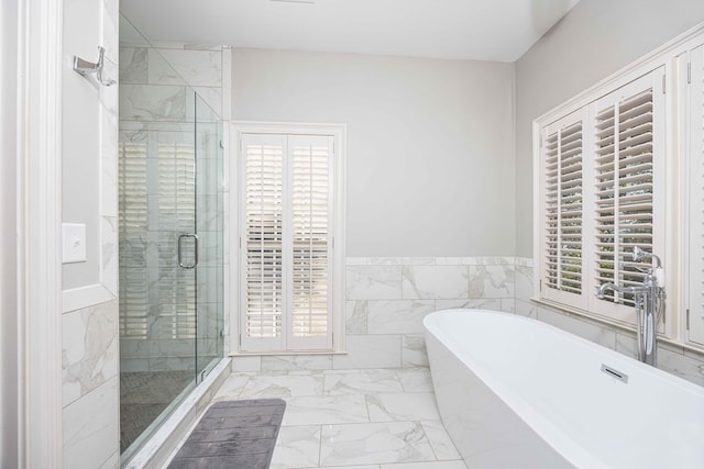 full bathroom with a shower stall, a wainscoted wall, a freestanding tub, marble finish floor, and tile walls