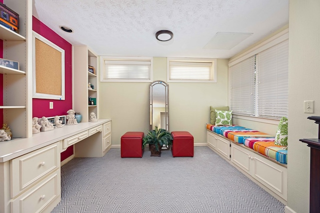 bedroom with light carpet, a textured ceiling, built in study area, and baseboards