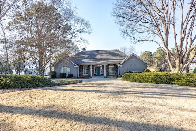 view of front of house with stucco siding, a chimney, and a front yard