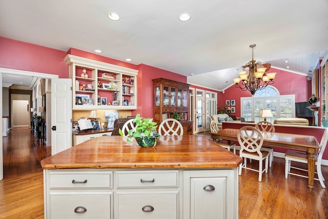 kitchen with light wood-type flooring, a notable chandelier, open floor plan, butcher block counters, and lofted ceiling