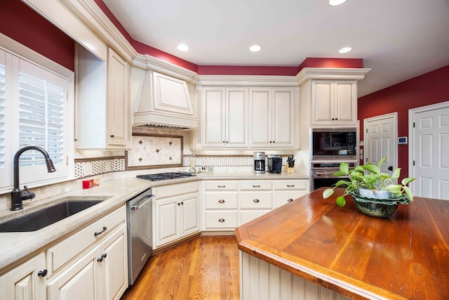 kitchen with a sink, backsplash, appliances with stainless steel finishes, and custom range hood