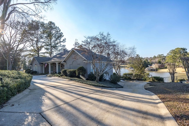 view of front facade featuring concrete driveway, a water view, and stucco siding