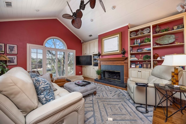 living area with visible vents, lofted ceiling, a fireplace, wood finished floors, and a ceiling fan