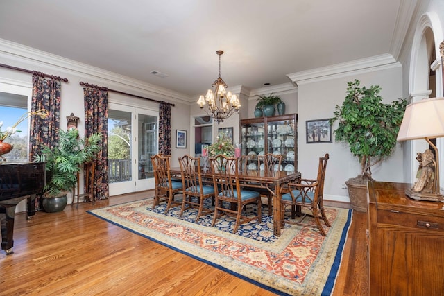 dining area featuring a notable chandelier, visible vents, ornamental molding, and wood finished floors