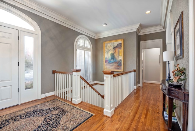 hallway with baseboards, an upstairs landing, wood finished floors, and crown molding