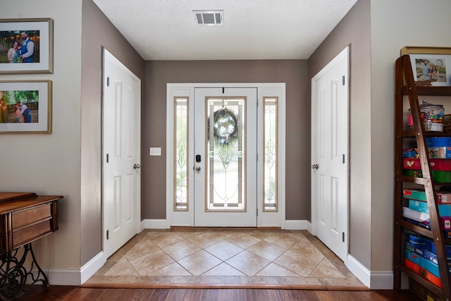 foyer with a textured ceiling and light hardwood / wood-style flooring