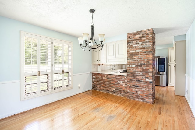 2951 Florence Dr, Columbus, GA 31907 - kitchen with light wood finished floors, a chandelier, smart refrigerator, a peninsula, and pendant lighting