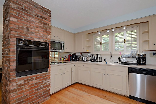 kitchen featuring appliances with stainless steel finishes, open shelves, a sink, light wood finished floors, and light countertops