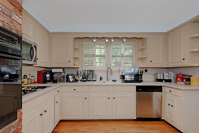 kitchen featuring open shelves, black appliances, a sink, and decorative backsplash