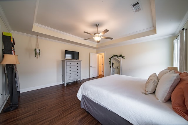 bedroom with dark wood-type flooring, a tray ceiling, and crown molding