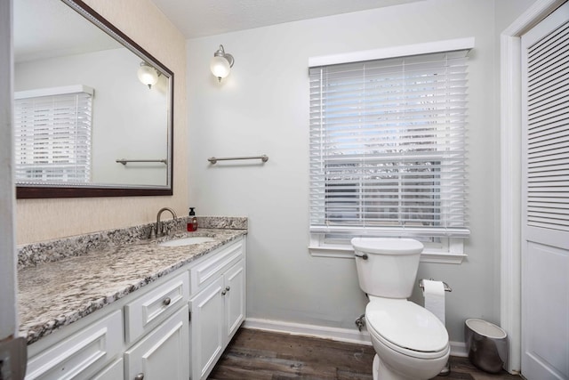 bathroom with toilet, vanity, and wood-type flooring