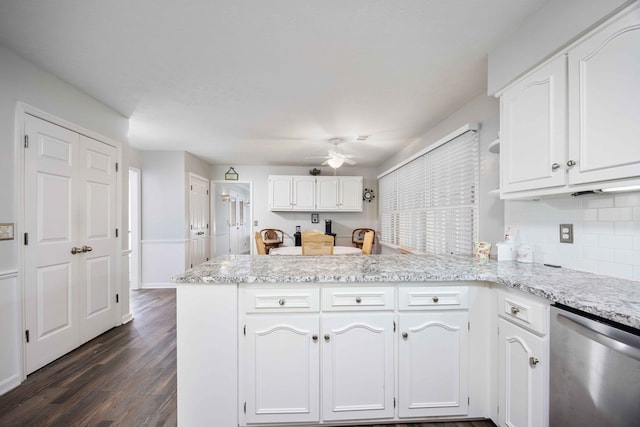 kitchen featuring dark hardwood / wood-style floors, stainless steel dishwasher, kitchen peninsula, white cabinets, and decorative backsplash