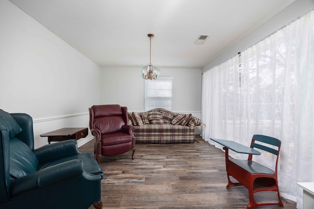 living room with dark wood-type flooring and a notable chandelier