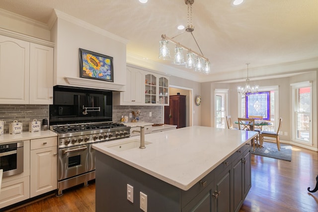 kitchen with appliances with stainless steel finishes, a center island with sink, crown molding, and white cabinets