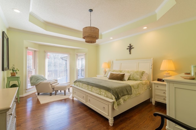 bedroom with a tray ceiling, dark wood-style floors, and a textured ceiling