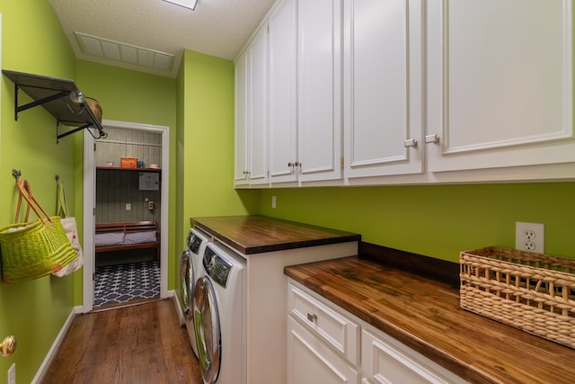 laundry room featuring visible vents, a textured ceiling, washing machine and dryer, cabinet space, and dark wood-style flooring