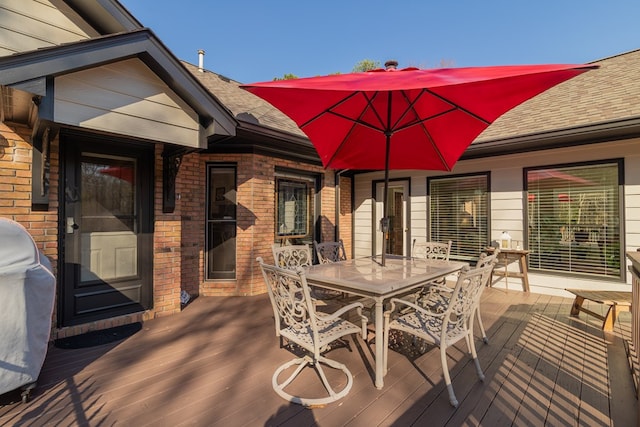 wooden terrace featuring area for grilling and outdoor dining area