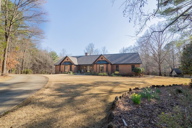 view of front of property with a chimney, a front lawn, and brick siding