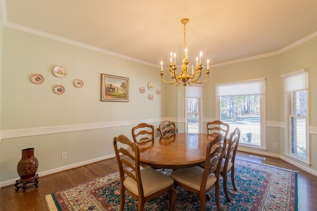 dining space with a textured ceiling, a notable chandelier, dark wood-style floors, and ornamental molding