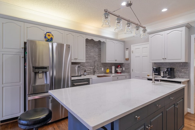 kitchen featuring white cabinets, wood finished floors, appliances with stainless steel finishes, and a sink