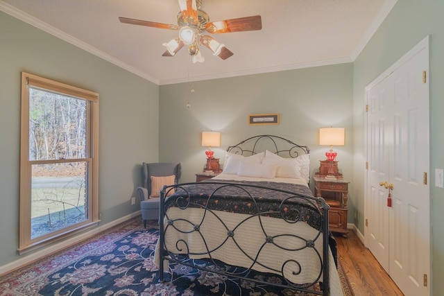 bedroom featuring ceiling fan, baseboards, wood finished floors, and crown molding