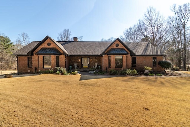 view of front of property featuring a front yard, brick siding, and a chimney