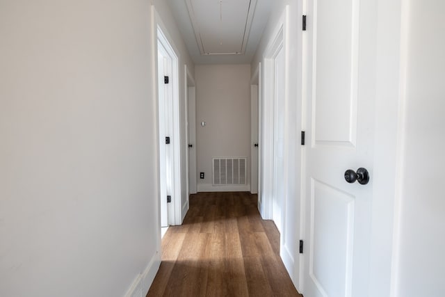 corridor with attic access, visible vents, baseboards, and wood finished floors