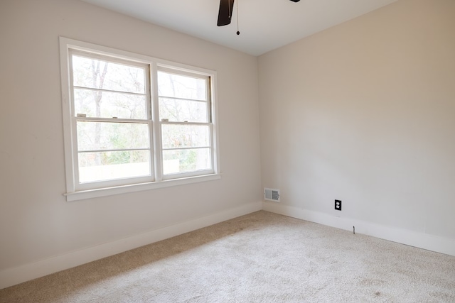 empty room with ceiling fan, carpet floors, visible vents, and baseboards