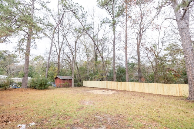 view of yard with a storage shed, an outbuilding, and fence