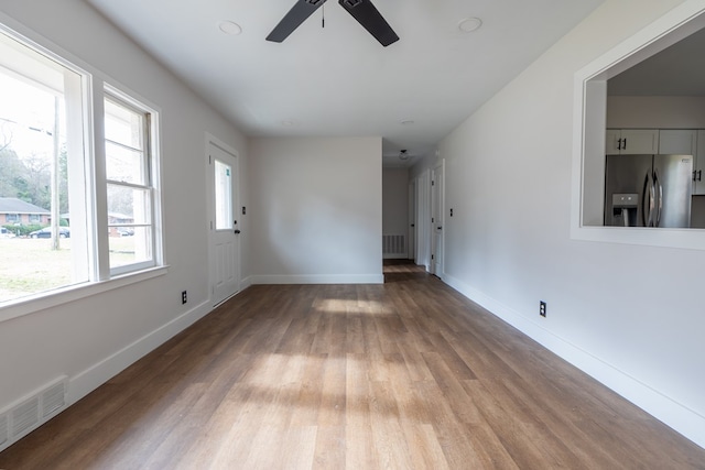 unfurnished room featuring ceiling fan, wood finished floors, visible vents, and baseboards