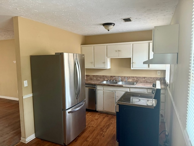 kitchen featuring appliances with stainless steel finishes, sink, white cabinets, dark hardwood / wood-style flooring, and a textured ceiling