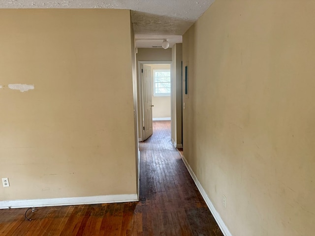 hallway featuring dark wood-type flooring and a textured ceiling