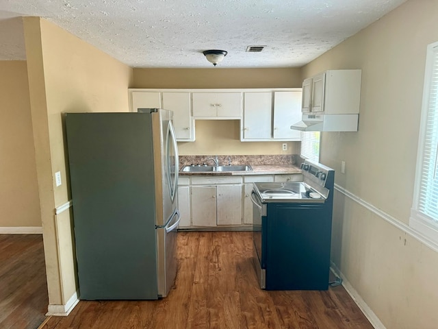 kitchen featuring electric stove, sink, stainless steel fridge, and white cabinets