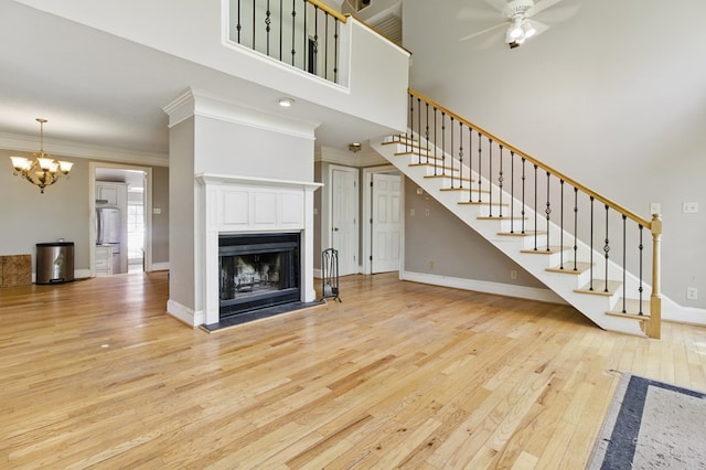 15635 US Highway 0027, Hamilton, GA 31811 - unfurnished living room featuring light wood finished floors, baseboards, ceiling fan with notable chandelier, stairway, and a fireplace