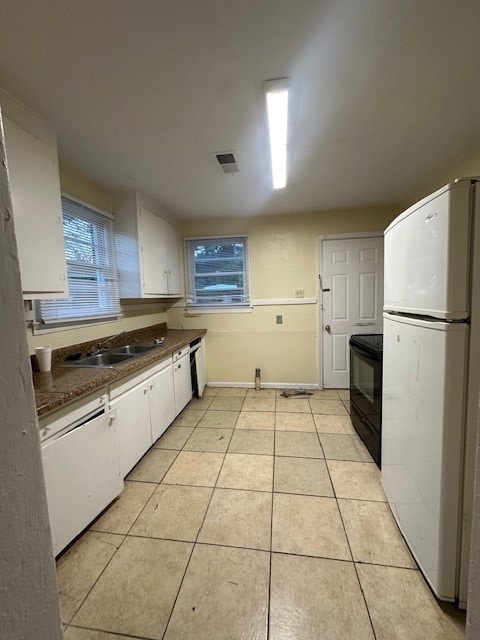 kitchen with white cabinets, white appliances, light tile patterned flooring, and sink