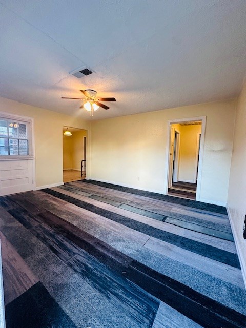 empty room with dark hardwood / wood-style flooring and ceiling fan