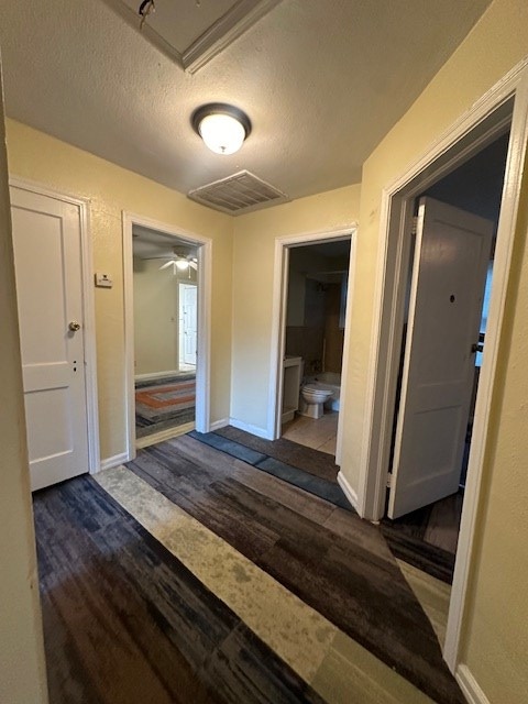 hall featuring a textured ceiling and dark wood-type flooring