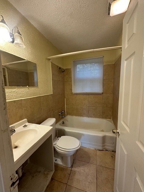 bathroom with tile patterned floors, tile walls, a textured ceiling, and toilet