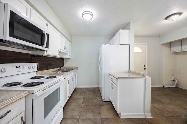 kitchen featuring white appliances, white cabinets, light countertops, a textured ceiling, and a sink