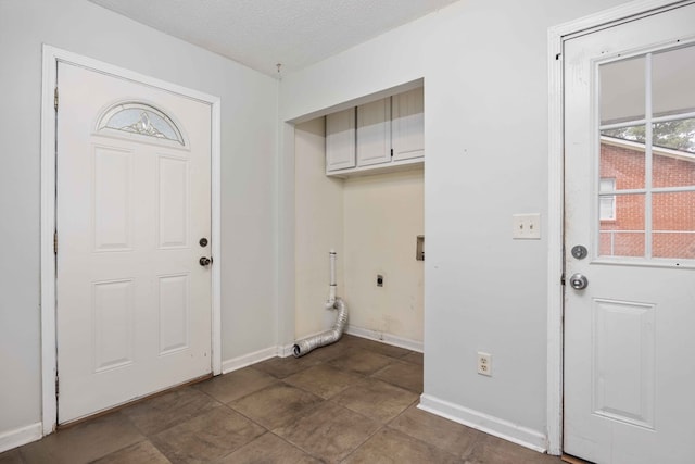 clothes washing area featuring a textured ceiling, cabinet space, electric dryer hookup, and baseboards